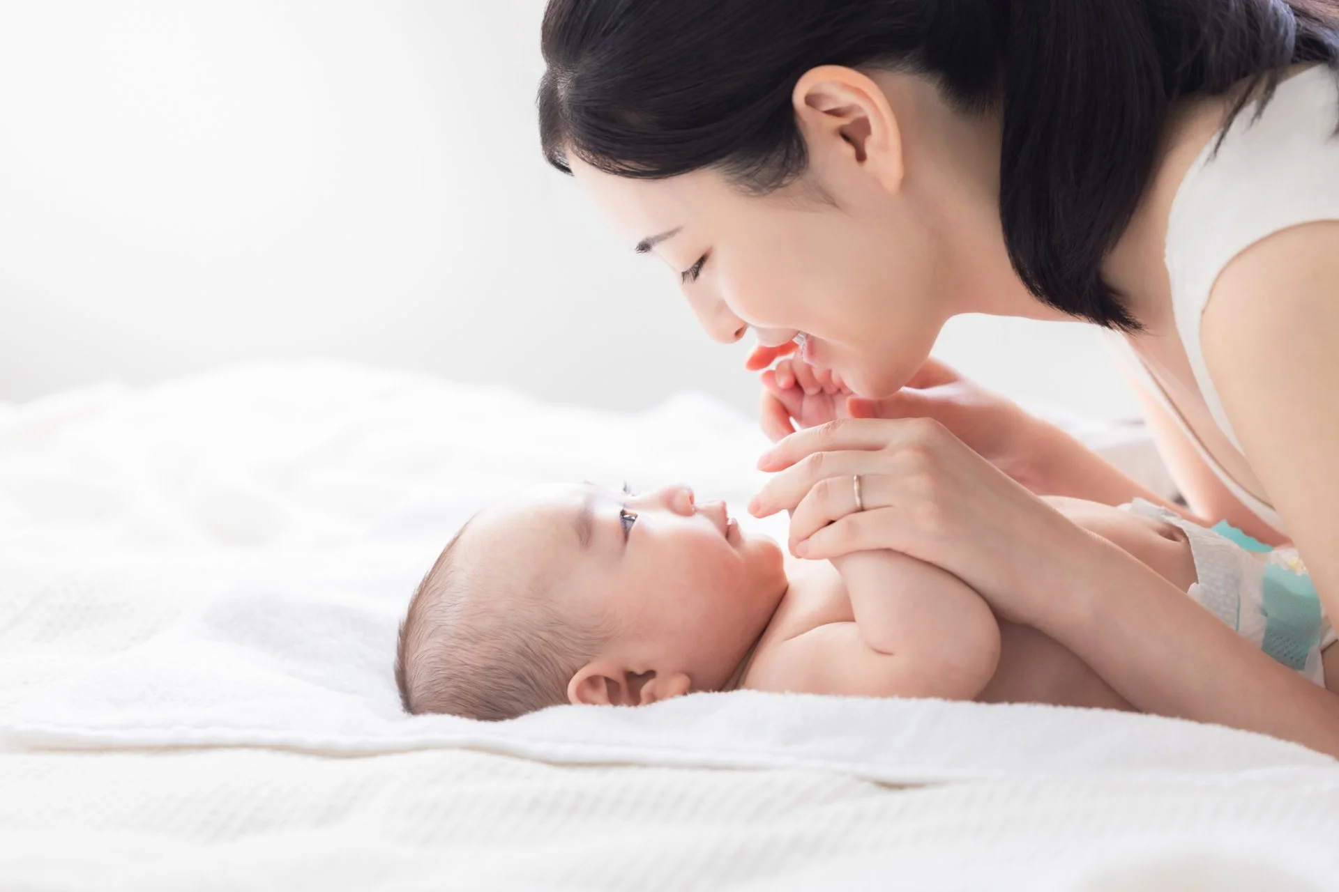 赤ちゃんを抱いた保護者が室内で子どもの様子を見守る場面